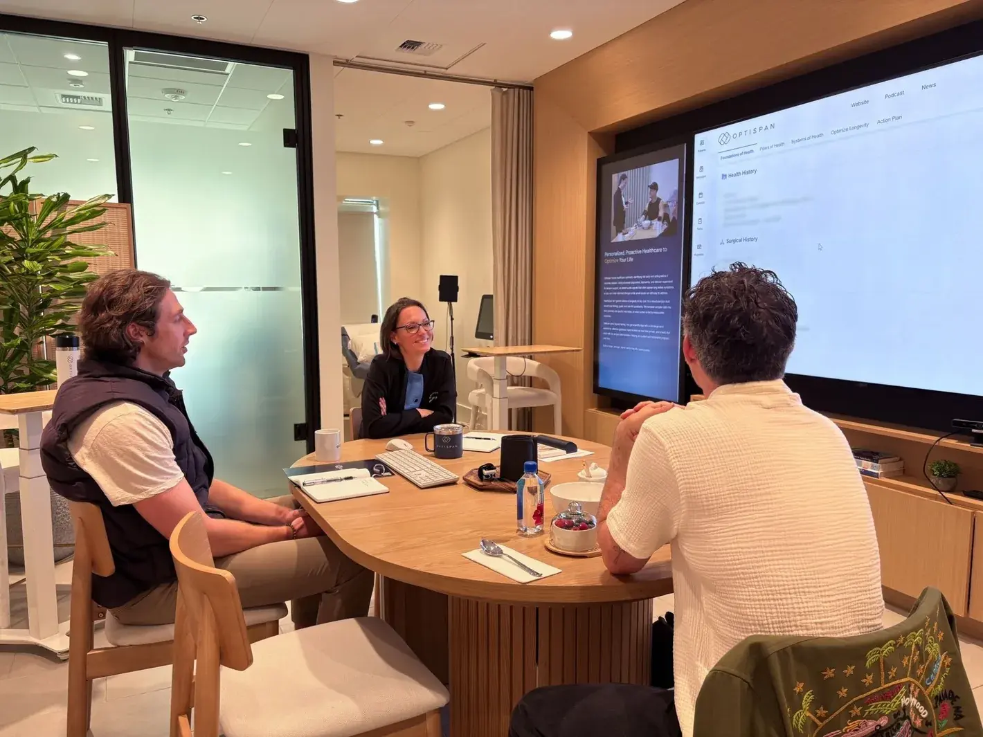 An Optispan clinician in conversation at the clinic, with the Optispan platform open on the wall screen